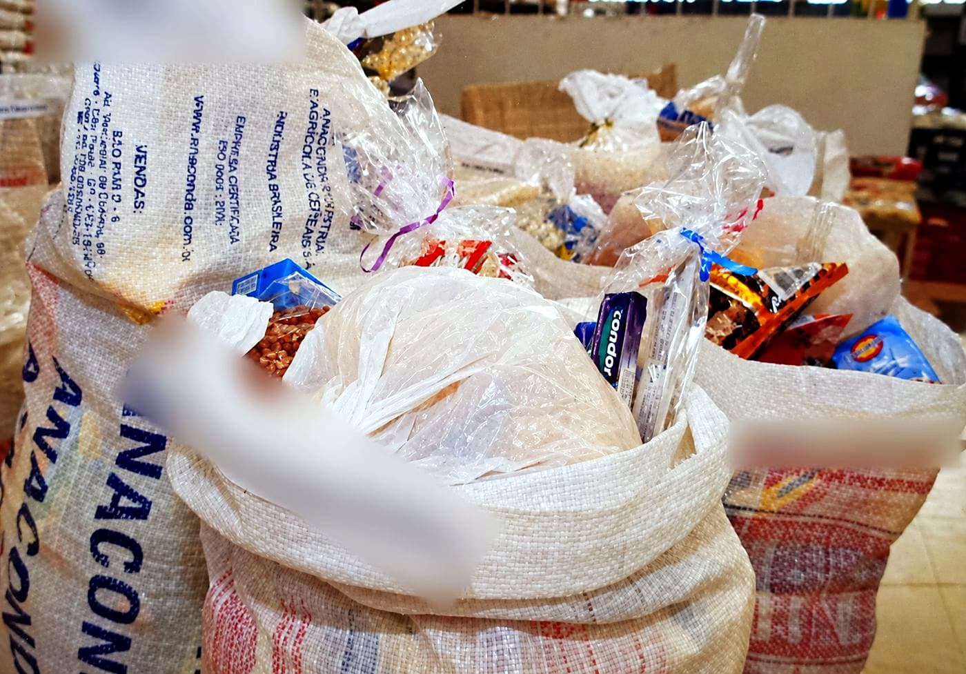 Sacos de alimentos cheios de feijão, arroz e itens de higiene, prontos para a entrega